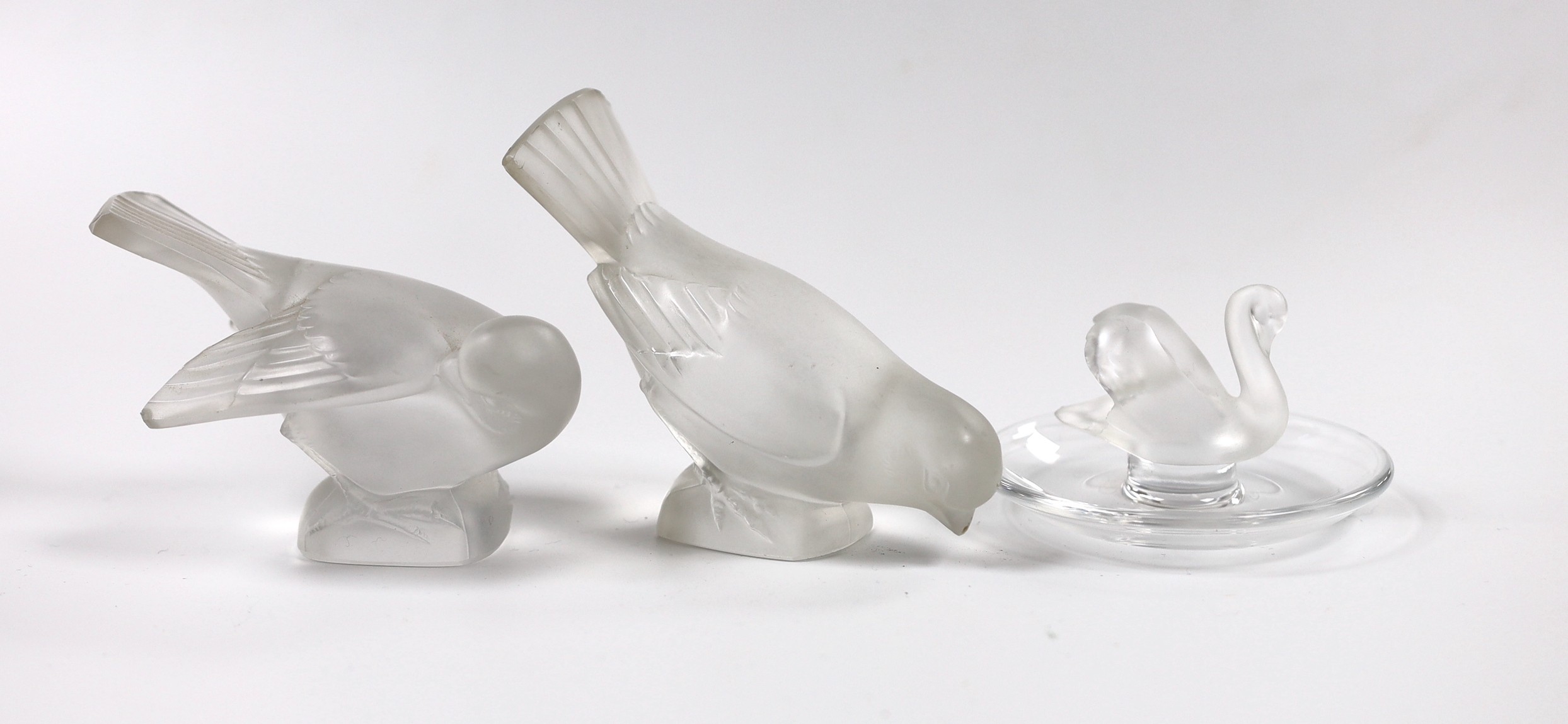 Two Lalique glass paperweights modelled as pecking birds, together with another Lalique swan modelled pin dish